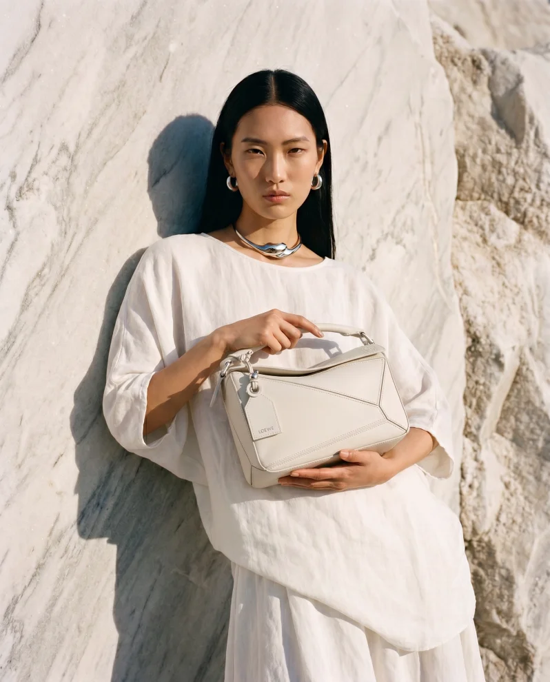 Model with white handbag against marble