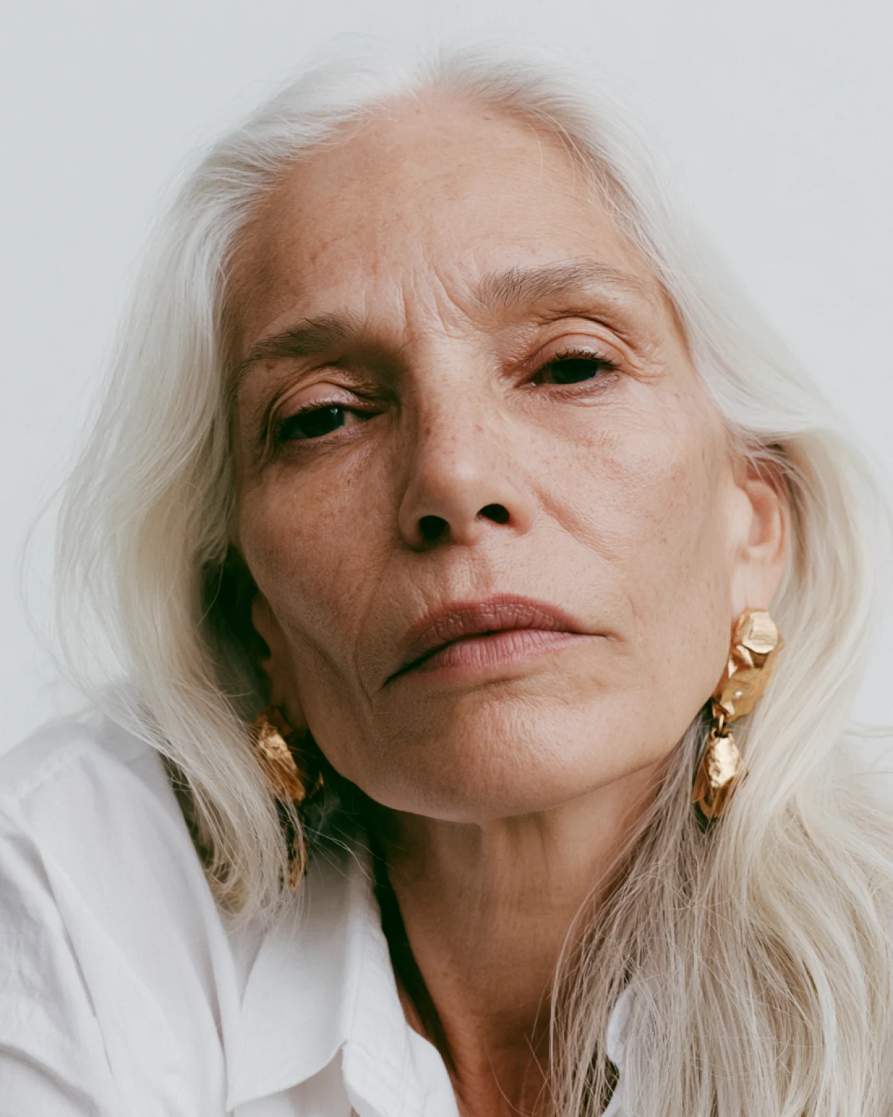 Portrait of a silver-haired model with gold earrings